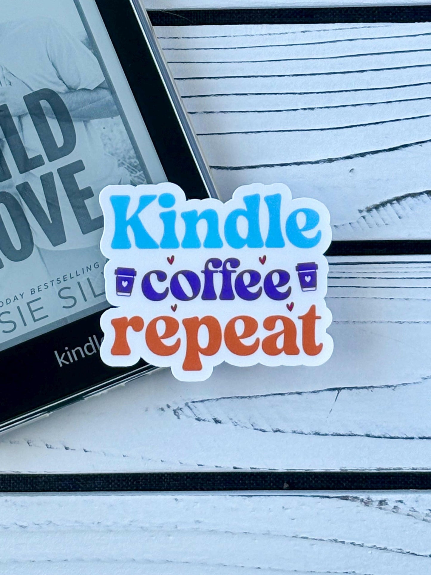 Sticker that says ‘Kindle Coffee Repeat’ in colorful retro text on a white background