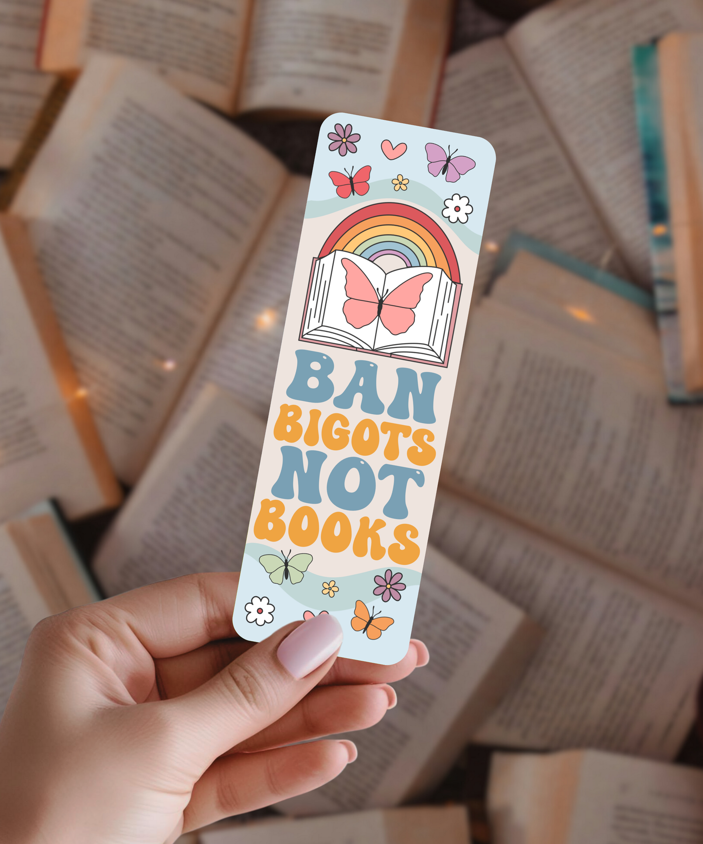 Hand holding a colorful bookmark with text and illustrations on a background of open books.