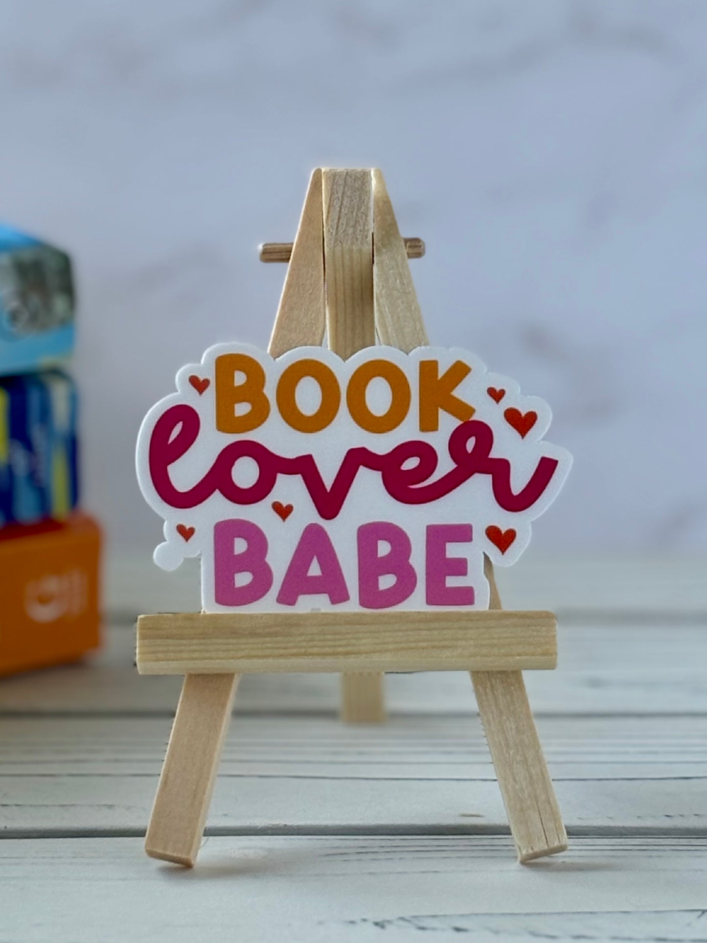 Decorative sticker with 'Book Lover Babe' text on a small wooden easel.