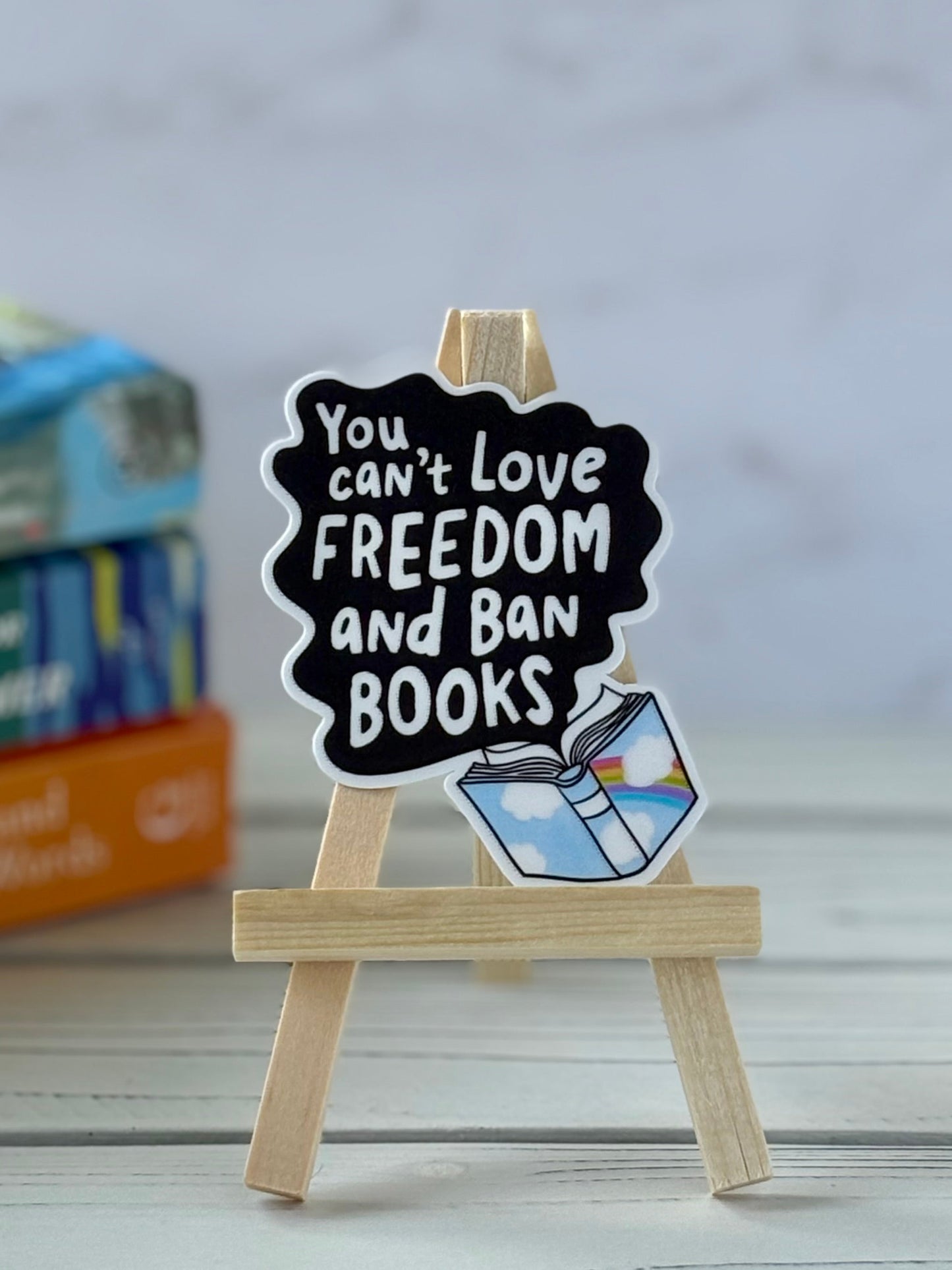 Sticker showing black speech bubble from open book with white text “You Can’t Love Freedom and Ban Books”