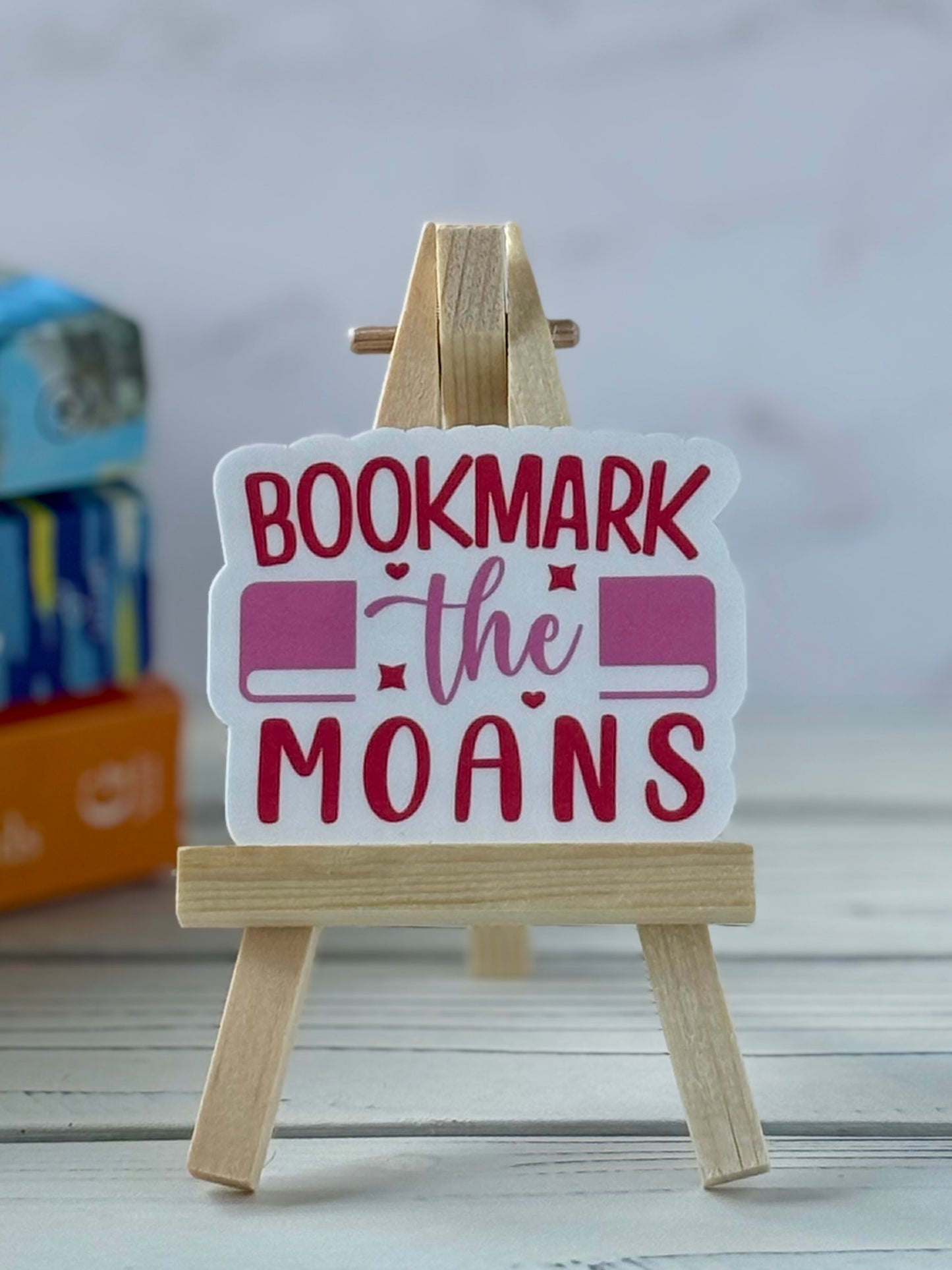 Sticker with retro pink and red text saying “Bookmark the Moans”