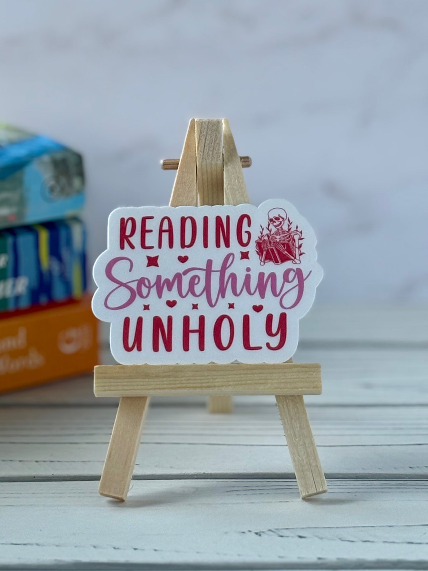 Retro pink and red text sticker saying “Reading Something Unholy.”