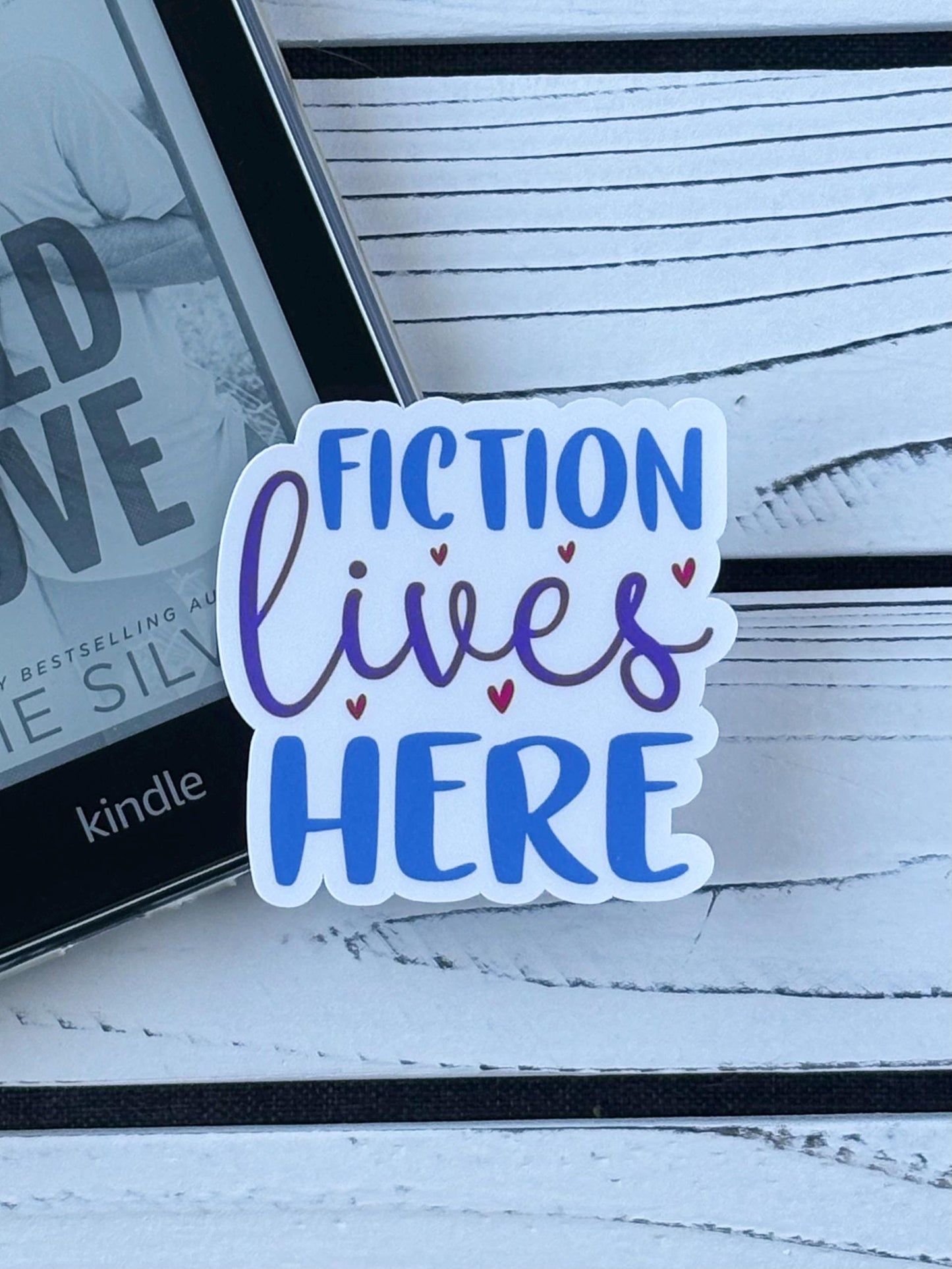 Sticker that says ‘Fiction Lives Here’ in bold retro lettering on a white background