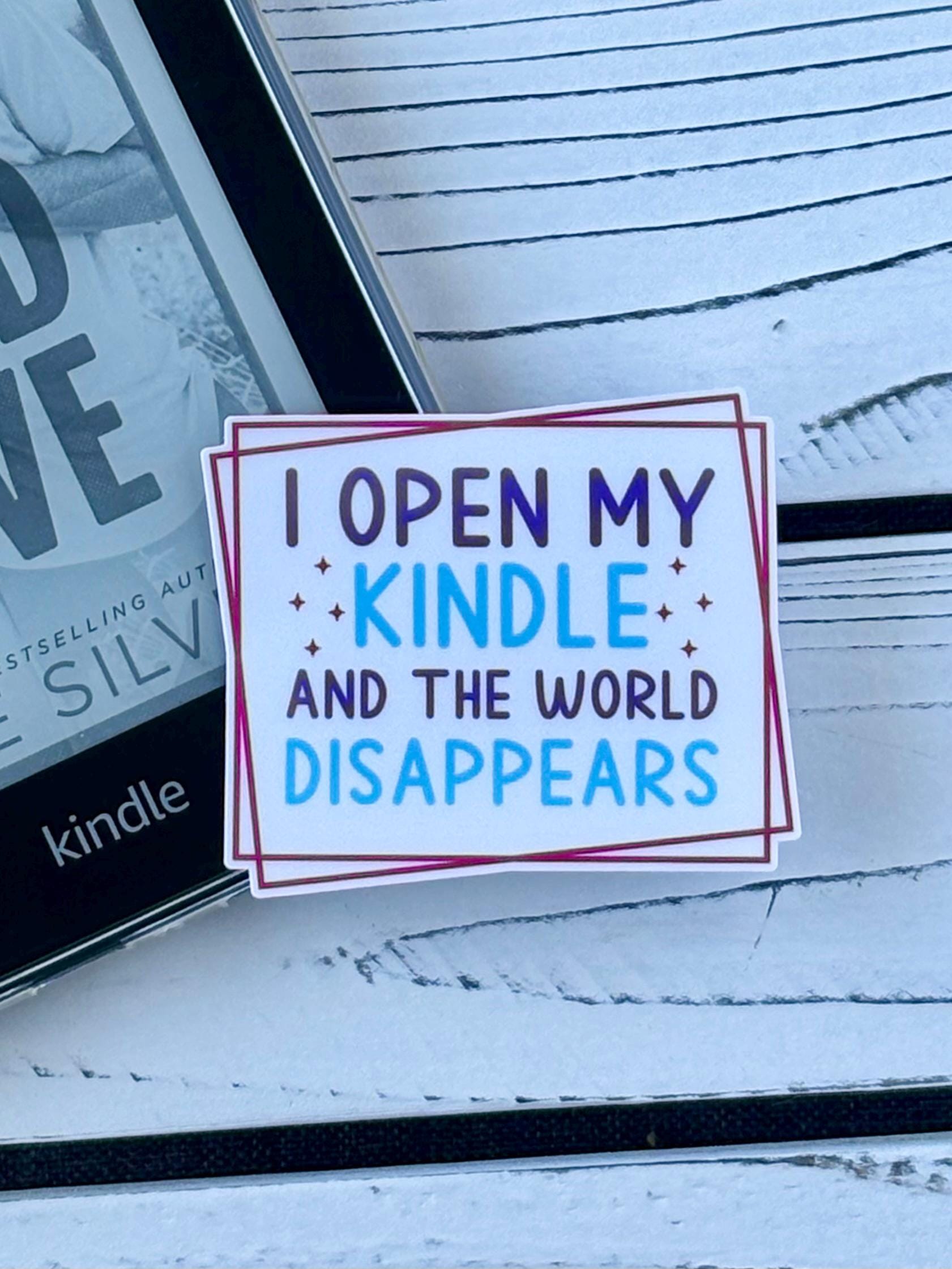 Sticker that says ‘I Open My Kindle and the World Disappears’ in retro-style text on a white background