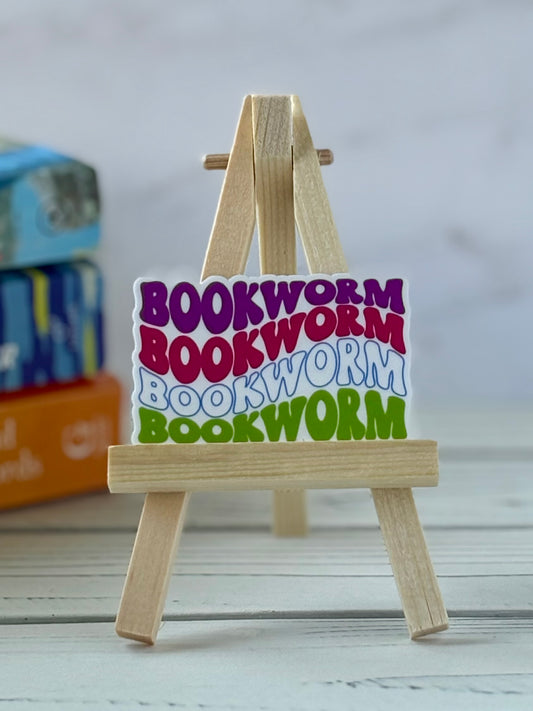 Colorful 'bookworm' retro vinyl sticker on a small wooden easel with a blurred background