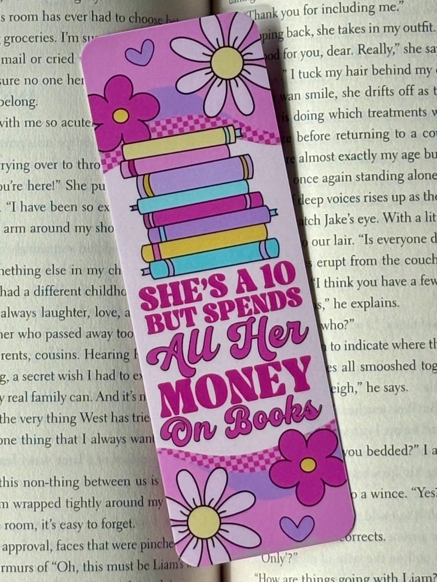 Colorful bookmark with floral designs and text reading “She’s A 10 But Spends All Her Money On Books” on a book page background