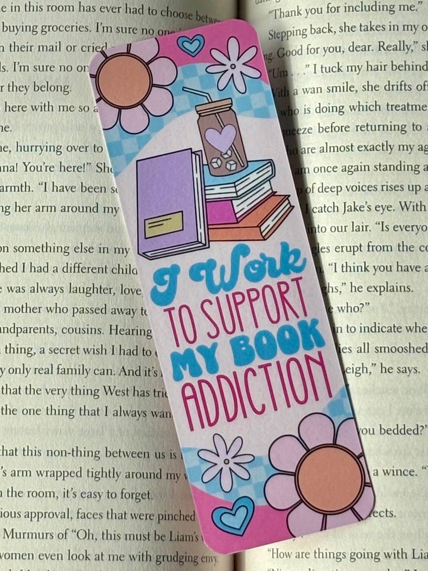 Colorful bookmark with text 'I Work to Support My Book Addiction' on a book page background
