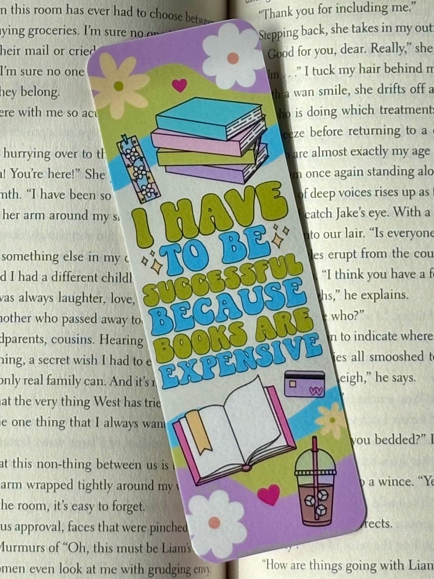 Colorful bookmark with text that says “I Have To Be Successful Because Books Are Expensive” and illustrations on a book page background