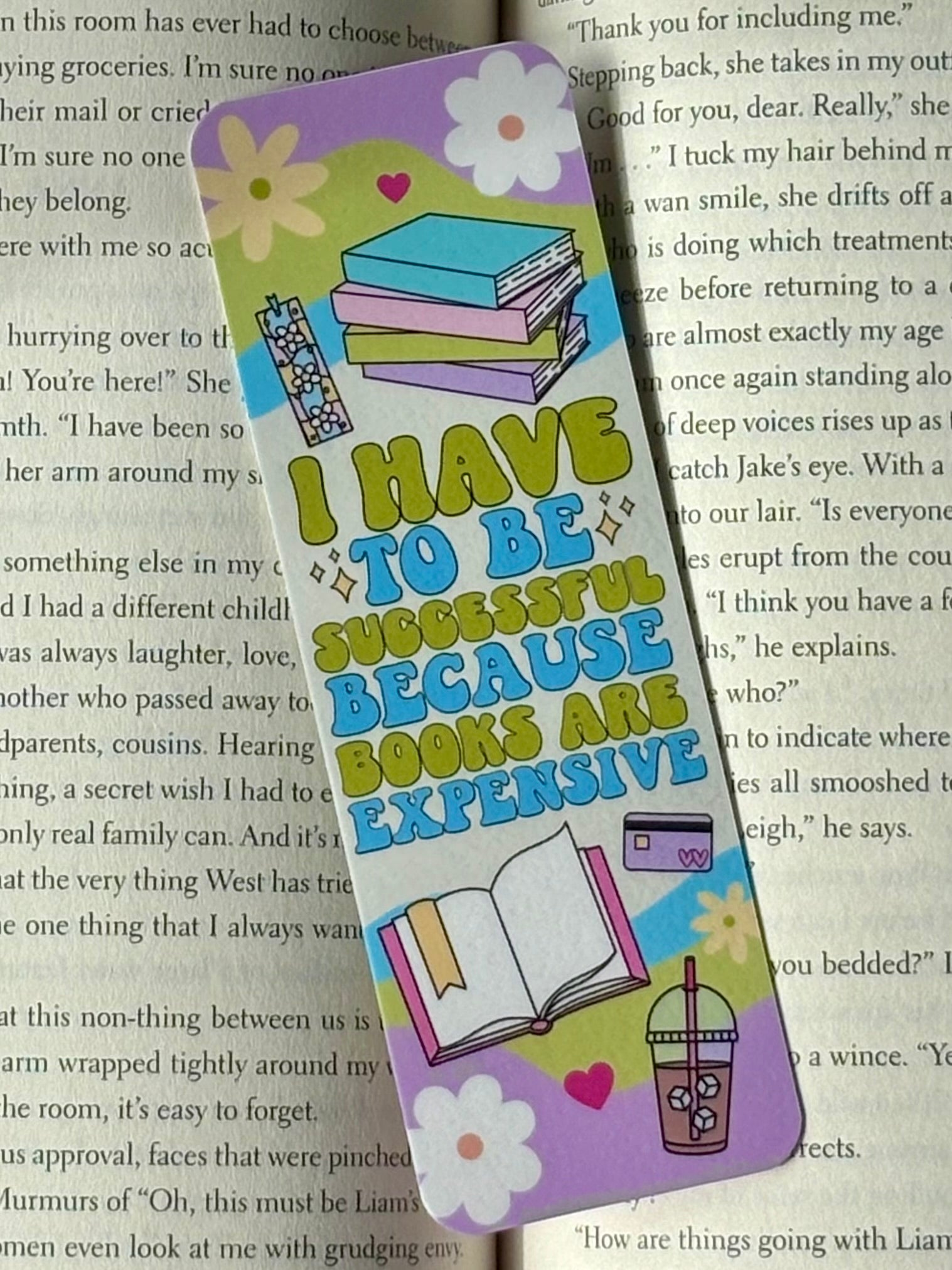 Colorful bookmark with text that says “I Have To Be Successful Because Books Are Expensive” and illustrations on a book page background