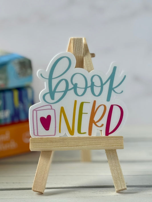 Colorful 'Book Nerd' sticker on a wooden stand with a blurred background