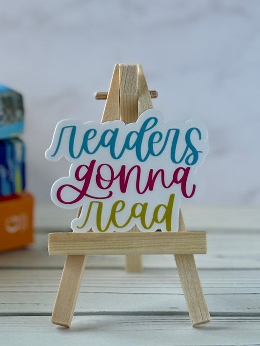 Colorful sign on a wooden stand with 'readers gonna read' text, placed on a light surface.