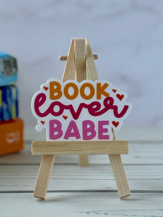 Decorative sticker with 'Book Lover Babe' text on a small wooden easel.