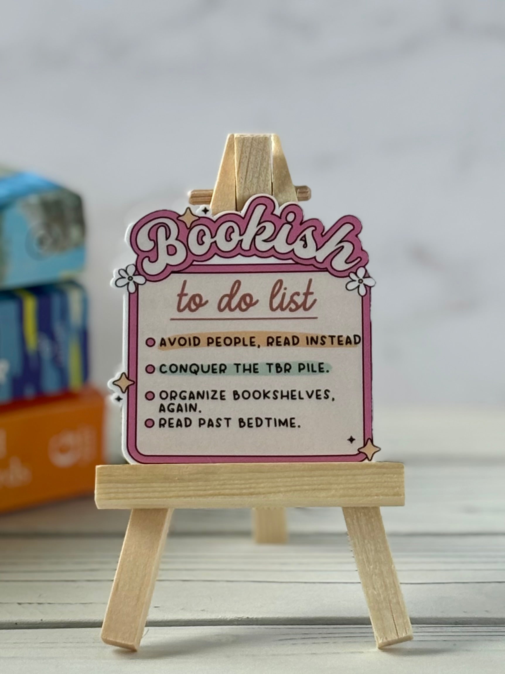 Wooden easel with a 'Bookish to do list' sign on a neutral background