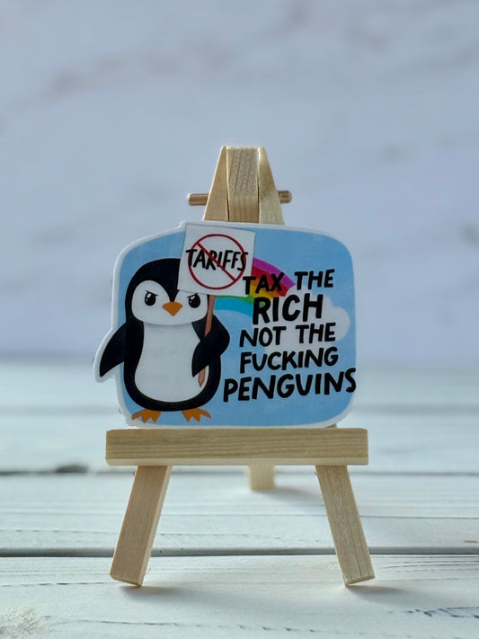 Sticker with penguin holding a crossed-out “tariffs” sign; rainbow background with black text “Tax the rich not the f*cking penguins”
