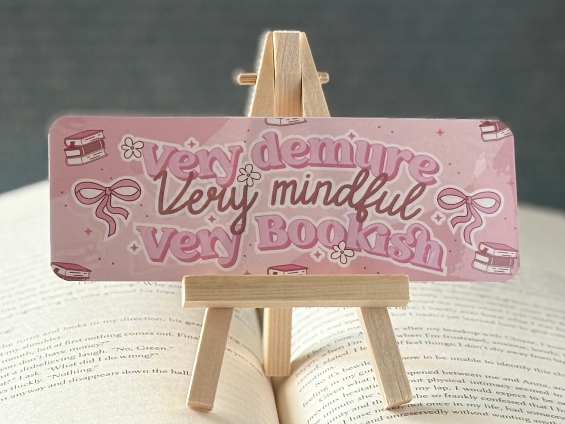 Pink bookmark with text on a wooden stand over an open book
