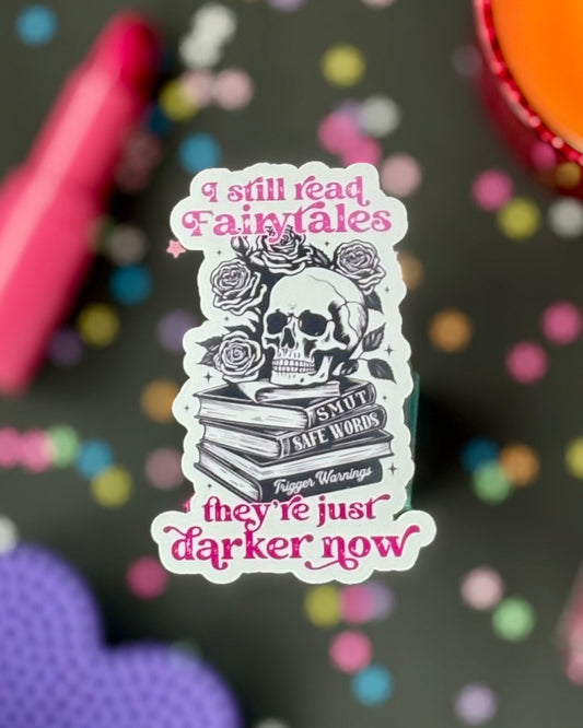 Sticker design with hot pink text over a book stack labeled “smut,” “safe words,” and “trigger warnings.” Skull and roses on top.