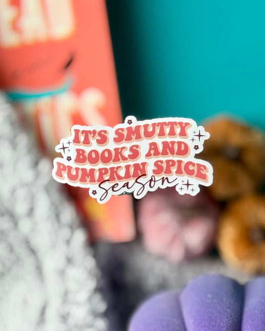 Sticker that says “It’s Smutty Books And Pumpkin Spice Season” in retro orange text on white vinyl