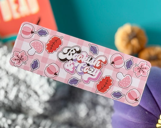 Bookmark with retro text “Bookish & Cozy” on large pink plaid background in warm fall tones