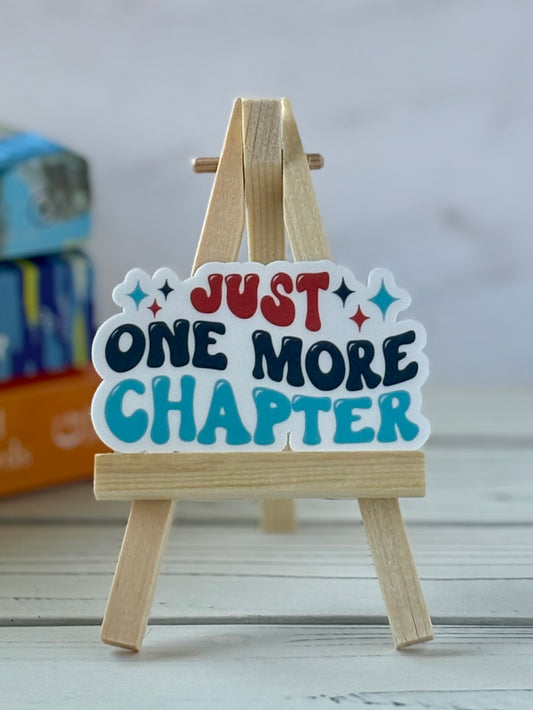 Vinyl sticker with 'Just One More Chapter' text on a small wooden easel.