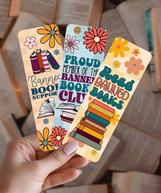 Three colorful bookmarks held by a hand with a blurred bookshelf background