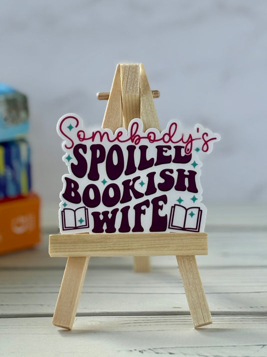 Wooden stand with a vinyl sticker reading 'Somebody's Spoiled Bookish Wife' on a light background.